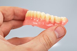 Close-up of hand holding full denture