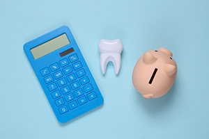 A piggy bank, calculator and model tooth on a blue background